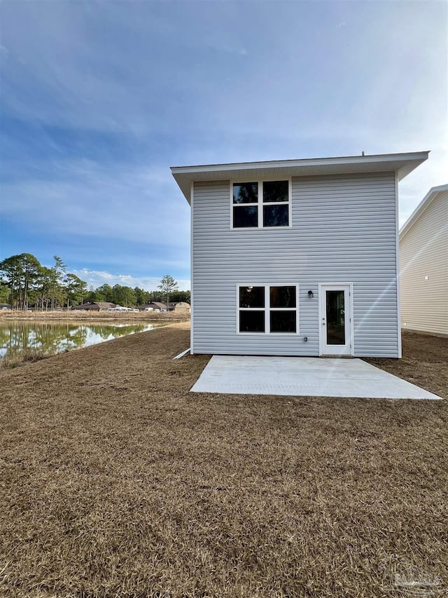 back of property featuring a water view, a lawn, and a patio area