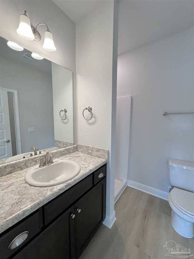 bathroom featuring walk in shower, vanity, toilet, and hardwood / wood-style floors