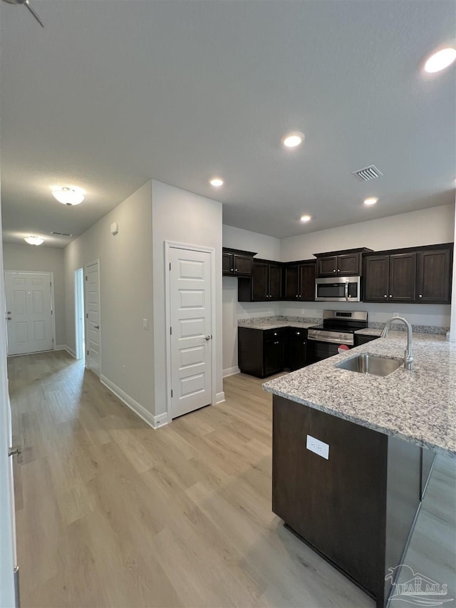 kitchen featuring light stone counters, stainless steel appliances, sink, and light wood-type flooring