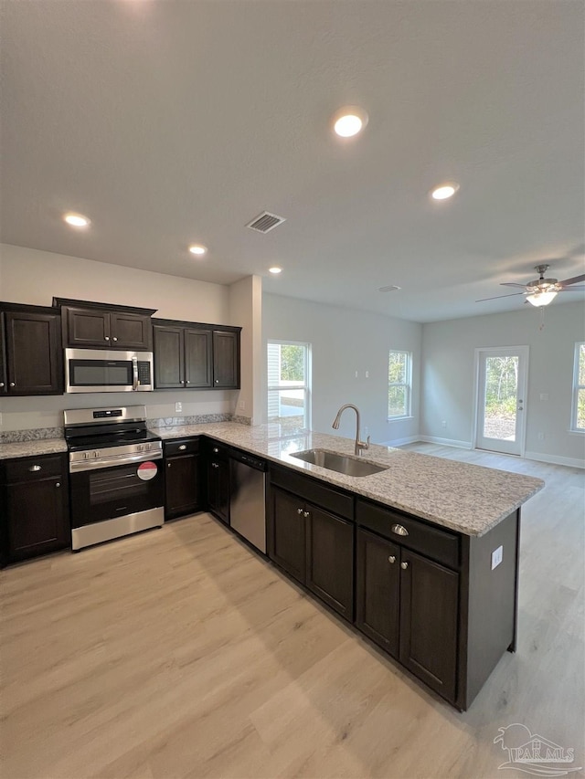 kitchen with stainless steel appliances, sink, a wealth of natural light, and light hardwood / wood-style flooring