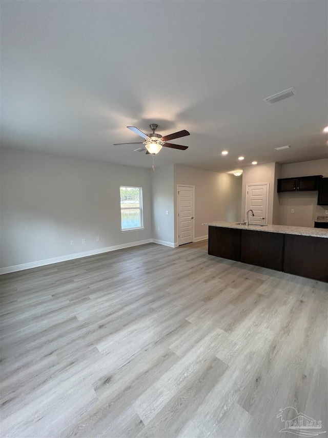 unfurnished living room featuring ceiling fan, sink, and light hardwood / wood-style flooring