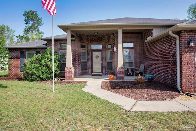 doorway to property with brick siding and a lawn