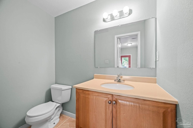 half bath featuring toilet, tile patterned flooring, baseboards, and vanity