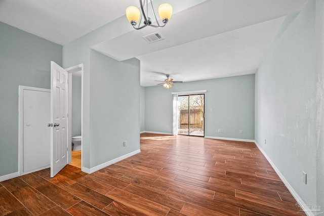 interior space featuring baseboards, visible vents, wood finished floors, and ceiling fan with notable chandelier