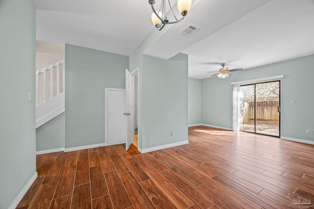 interior space with ceiling fan with notable chandelier, wood finished floors, visible vents, and baseboards