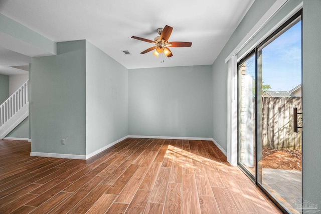 spare room featuring stairs, wood finished floors, and baseboards