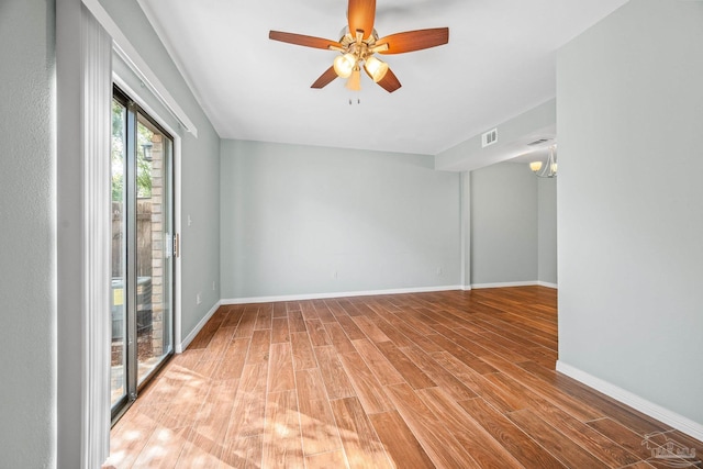empty room with visible vents, wood finished floors, a ceiling fan, and baseboards