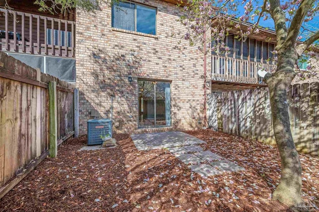 back of property with a patio, fence, central AC, and brick siding