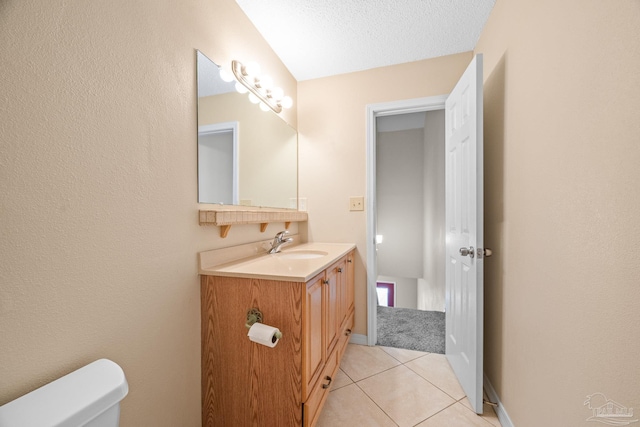 bathroom featuring a textured ceiling, toilet, vanity, baseboards, and tile patterned floors
