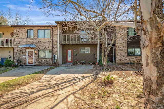 multi unit property with a balcony and brick siding