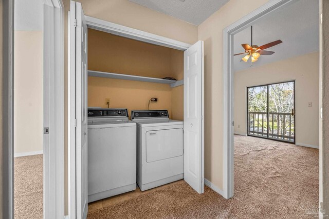 laundry area with ceiling fan, washing machine and dryer, light colored carpet, laundry area, and baseboards