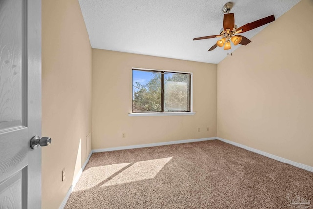 carpeted spare room featuring lofted ceiling, baseboards, and a textured ceiling