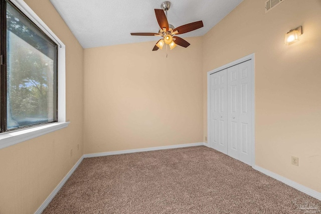 unfurnished bedroom featuring lofted ceiling, a closet, visible vents, carpet flooring, and baseboards