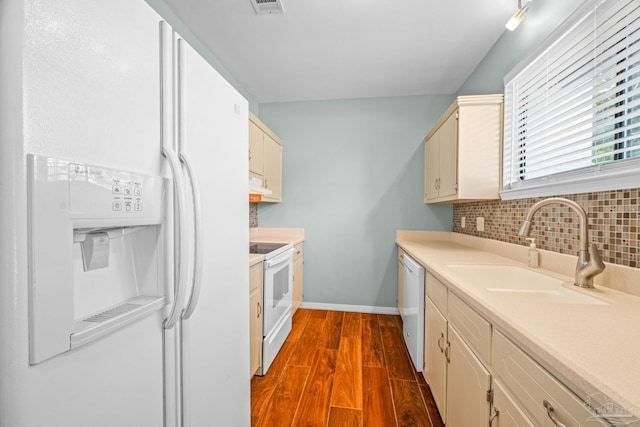 kitchen with white appliances, dark wood finished floors, backsplash, and a sink