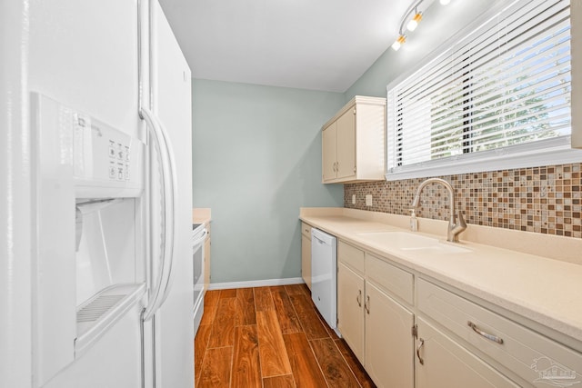 kitchen featuring dark wood finished floors, light countertops, decorative backsplash, a sink, and white appliances