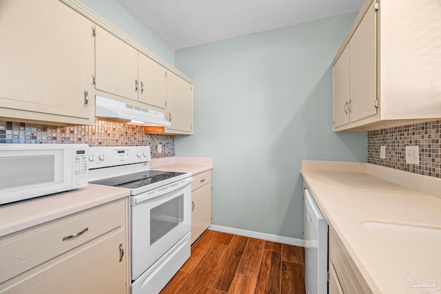 kitchen with under cabinet range hood, white appliances, baseboards, light countertops, and dark wood-style floors