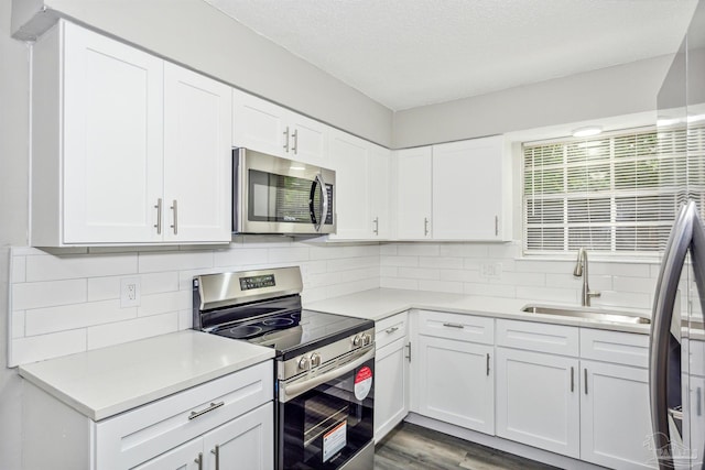 kitchen with appliances with stainless steel finishes, light hardwood / wood-style flooring, white cabinetry, and sink