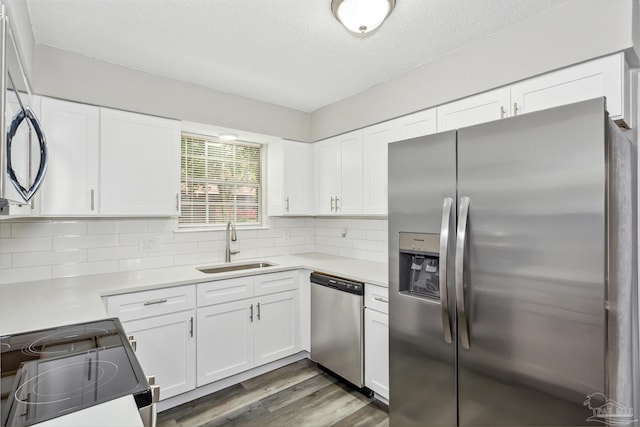 kitchen featuring appliances with stainless steel finishes, white cabinetry, dark hardwood / wood-style flooring, decorative backsplash, and sink