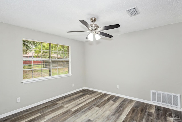 empty room with a textured ceiling, ceiling fan, and dark hardwood / wood-style flooring