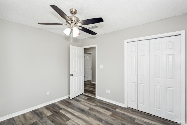 unfurnished bedroom with ceiling fan, a closet, dark wood-type flooring, and a textured ceiling