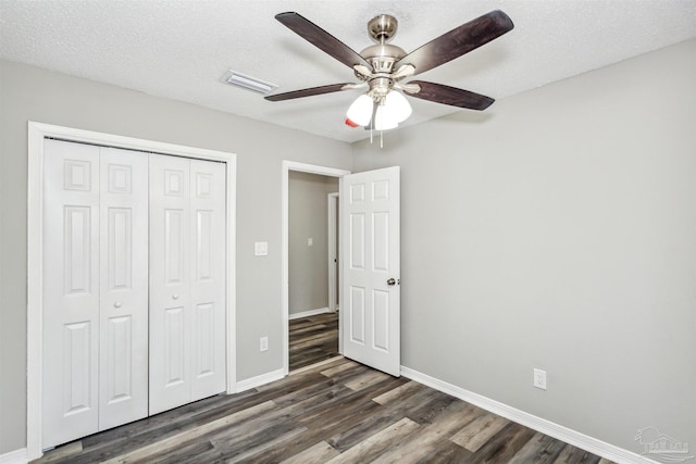 unfurnished bedroom featuring ceiling fan, a closet, dark hardwood / wood-style flooring, and a textured ceiling