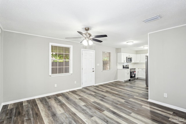 unfurnished living room with a textured ceiling, dark wood-type flooring, crown molding, and ceiling fan