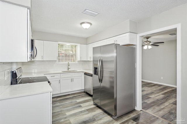 kitchen featuring a textured ceiling, white cabinets, stainless steel appliances, sink, and light wood-type flooring