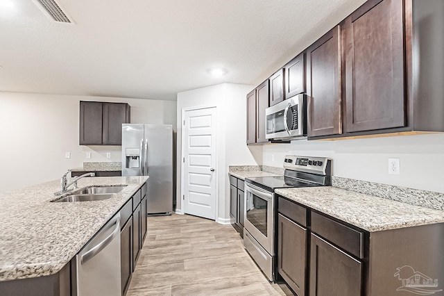 5805 Guinevere Ln, Milton, FL 32583 - kitchen with stainless steel appliances, a sink, dark brown cabinetry, and light wood-type flooring
