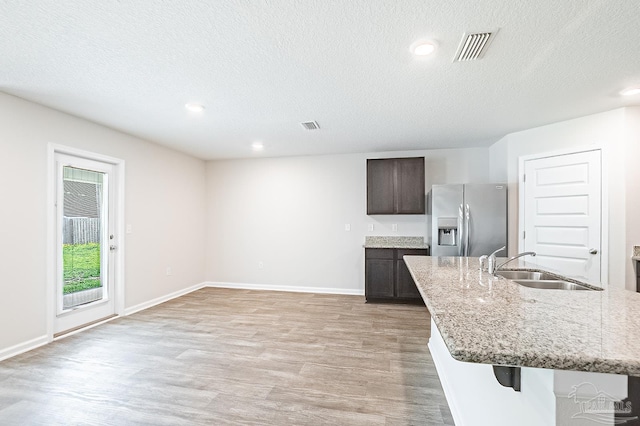 5805 Guinevere Ln, Milton, FL 32583 - kitchen with stainless steel fridge, light wood-style floors, a textured ceiling, a sink, and dark brown cabinets