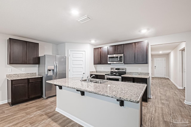 5805 Guinevere Ln, Milton, FL 32583 - kitchen with stainless steel appliances, a sink, light wood-style flooring, a breakfast bar, and dark brown cabinetry