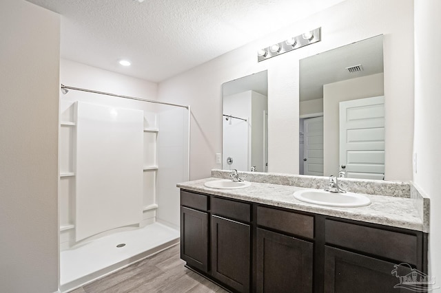 5805 Guinevere Ln, Milton, FL 32583 - bathroom featuring wood finished floors, a shower, double vanity, and a textured ceiling