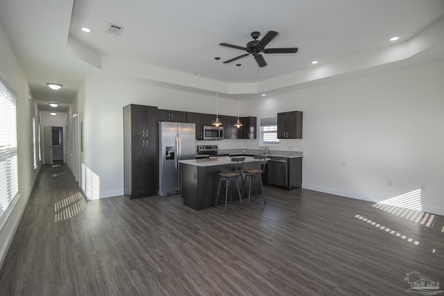 kitchen featuring appliances with stainless steel finishes, dark hardwood / wood-style flooring, a kitchen island, and a healthy amount of sunlight