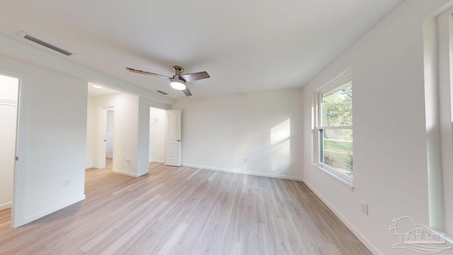 empty room with light wood-style floors, visible vents, and baseboards