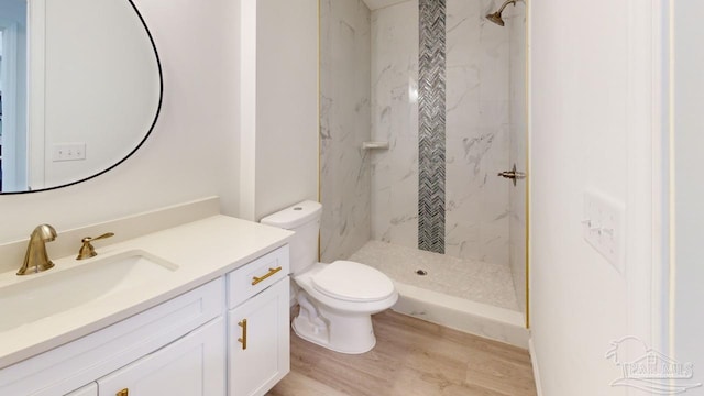 bathroom featuring a marble finish shower, toilet, vanity, and wood finished floors