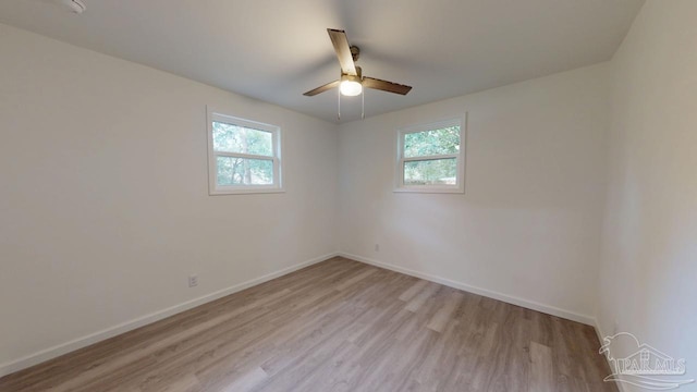 empty room featuring a wealth of natural light, baseboards, a ceiling fan, and light wood finished floors