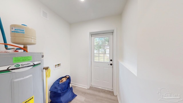 laundry room featuring visible vents, washer hookup, electric water heater, light wood finished floors, and baseboards