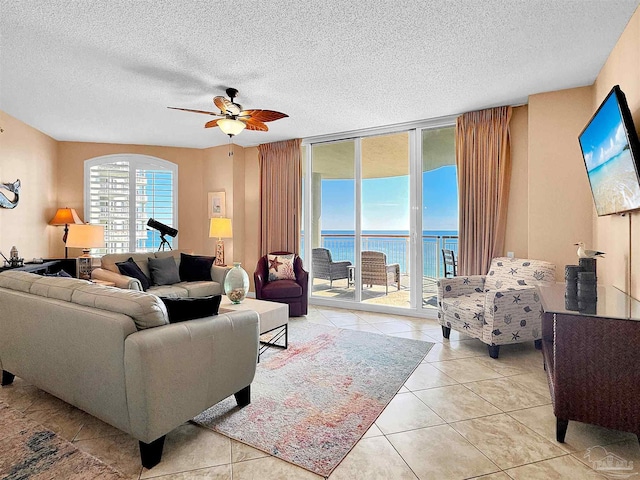 living room featuring light tile patterned flooring, a wall of windows, ceiling fan, and a textured ceiling