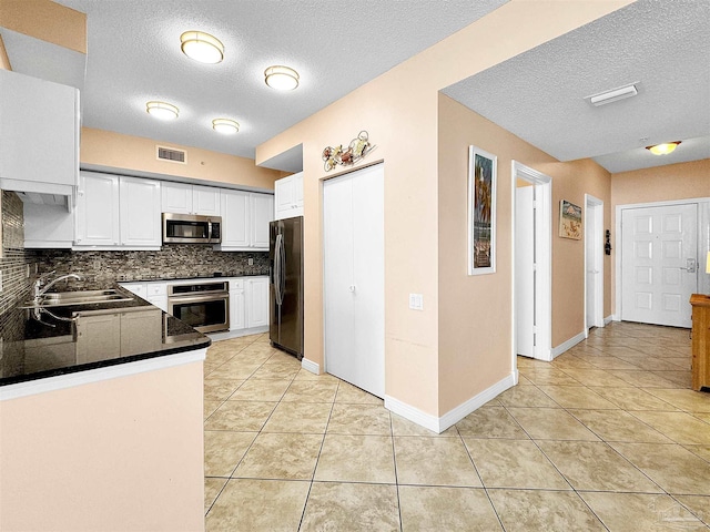 kitchen with white cabinetry, appliances with stainless steel finishes, sink, and light tile patterned floors