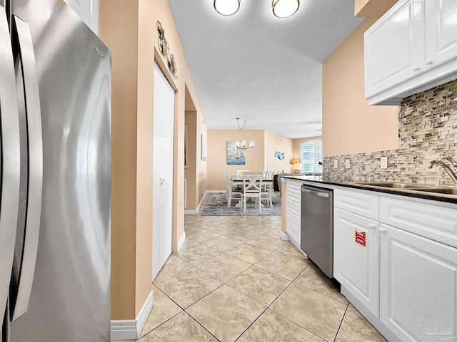 kitchen with pendant lighting, sink, stainless steel appliances, white cabinets, and decorative backsplash