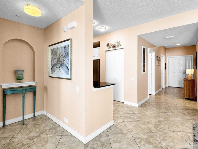 hallway featuring light tile patterned floors and a textured ceiling