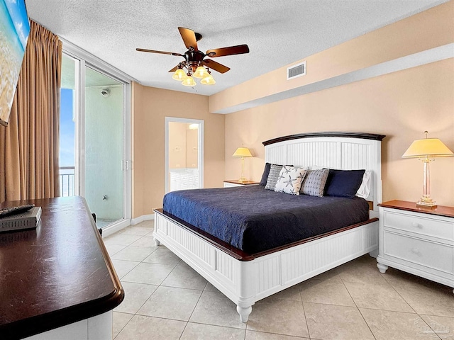 tiled bedroom featuring connected bathroom, ceiling fan, a wall of windows, and a textured ceiling