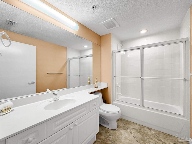 full bathroom with combined bath / shower with glass door, tile patterned flooring, vanity, toilet, and a textured ceiling