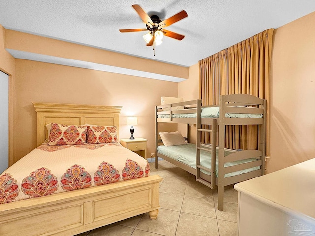 bedroom featuring ceiling fan, light tile patterned floors, and a textured ceiling