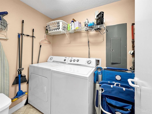 washroom featuring electric panel, washer and dryer, a textured ceiling, and light tile patterned flooring