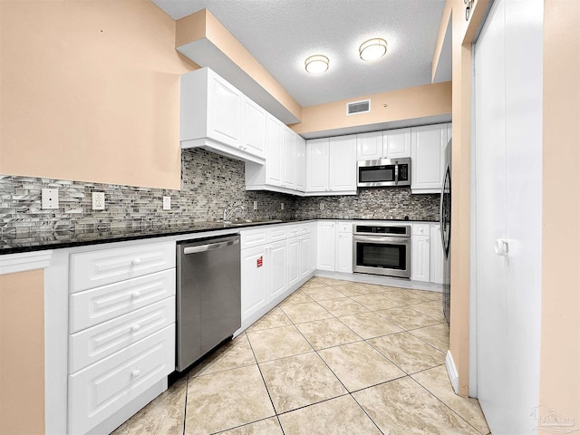 kitchen with decorative backsplash, light tile patterned flooring, white cabinets, and appliances with stainless steel finishes