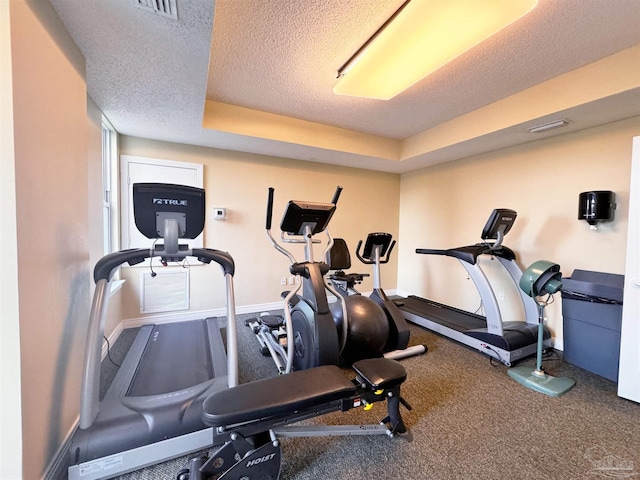 exercise room with a raised ceiling and a textured ceiling