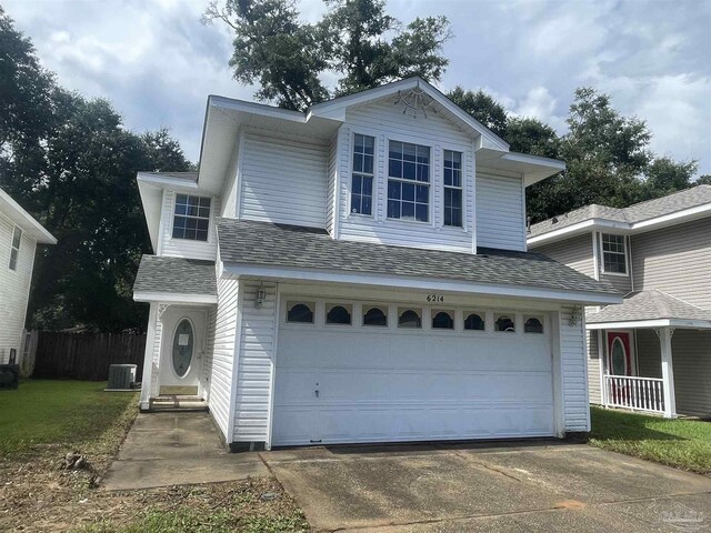 view of front of house with central air condition unit, a garage, and a front lawn