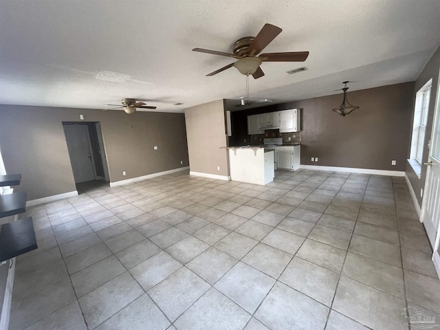 unfurnished living room with baseboards, visible vents, and a textured ceiling