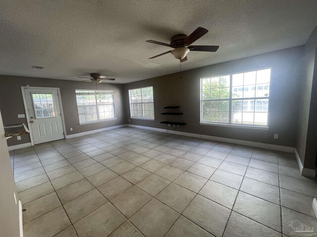 tiled empty room featuring a textured ceiling and ceiling fan