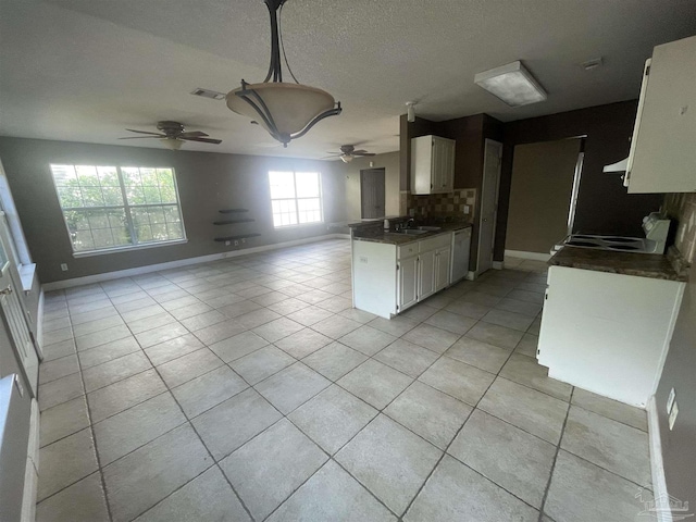 kitchen with a sink, visible vents, white cabinets, open floor plan, and dark countertops